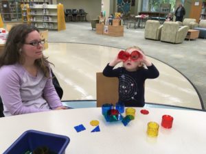 A child looks through red circular Crystal Climbers like binoculars.