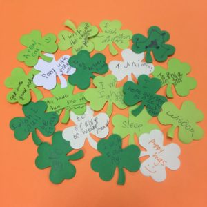 Cutout shamrock shapes with wishes written on them.