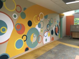 The previously scruffy wall is now painted with a mural of colorful circles.