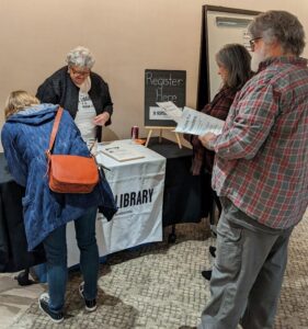 Three people wait in line to register for the Human Library Event. One of the Event volunteers checks them in.